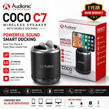 Audionic Coco C7 wireless speaker in dark gray with a matching retail box, shown on a white and black promotional background with feature callouts and a 1-year brand warranty badge.